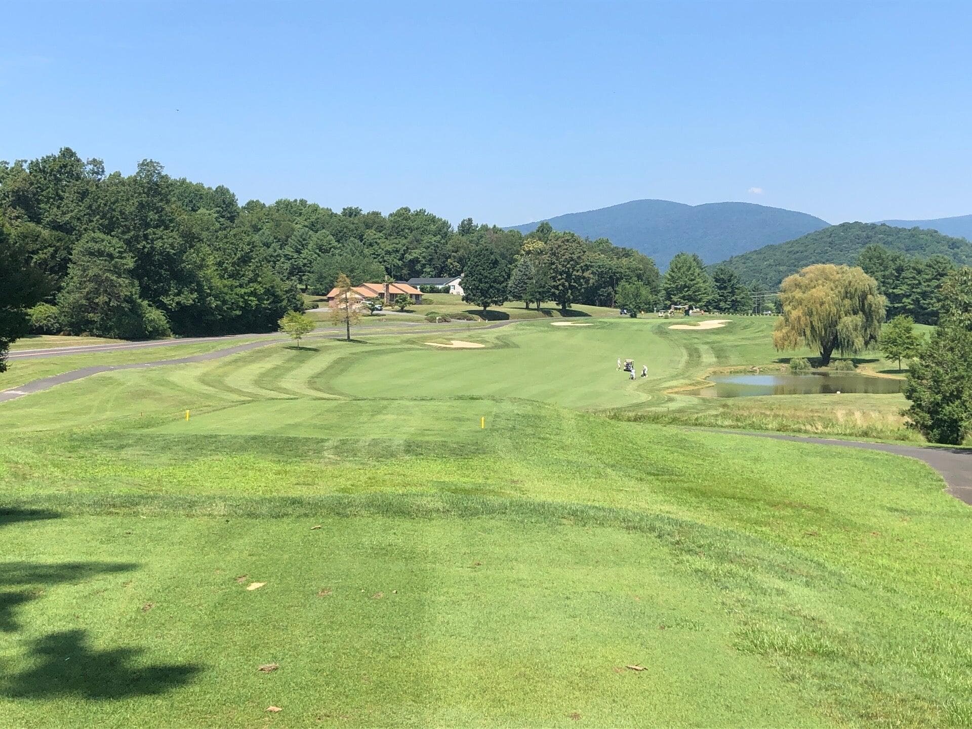A Greene Hills fairway looking toward the clubhouse, with weeping willows and the Blue Ridge ridgeline in the distance.